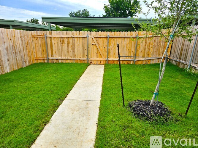 A backyard with a wooden fence and a concrete walkway.
