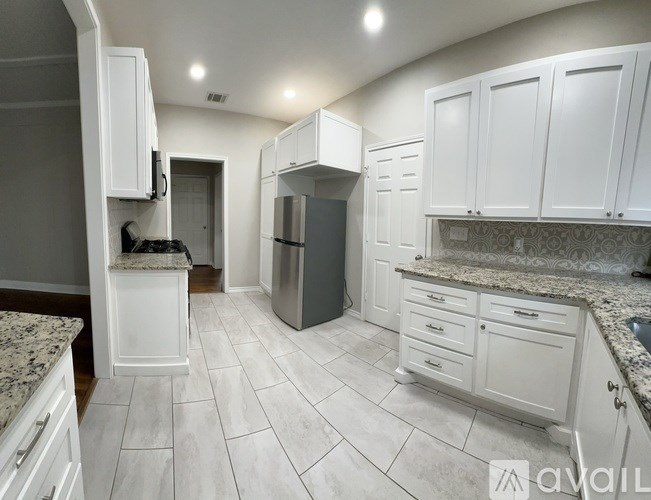 A kitchen with white cabinets and a marble countertop.