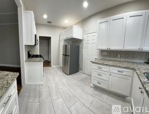 A kitchen with white cabinets and a marble countertop.