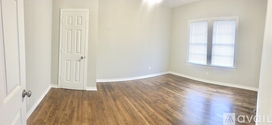 A room with a white door and wooden flooring.