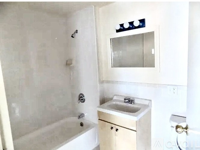 A white bathroom with a sink, mirror, and bathtub.