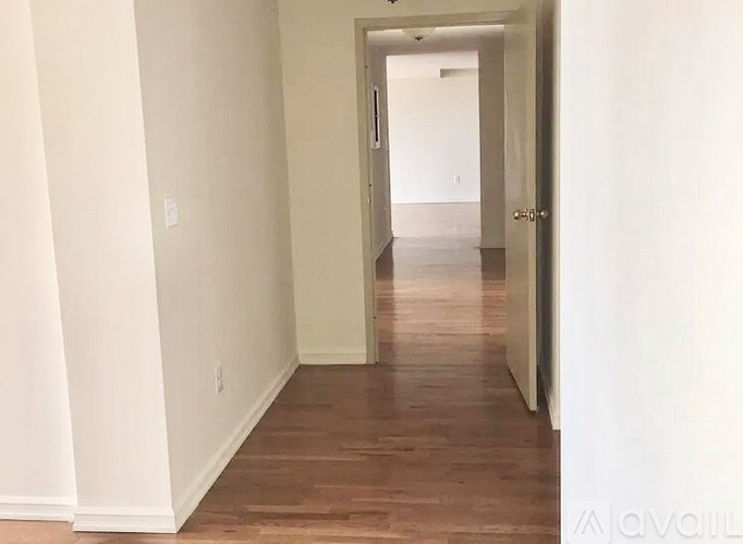 A long hallway with wood floors and white walls.