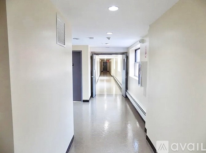 A long, narrow hallway with doors on both sides and a light on the ceiling.