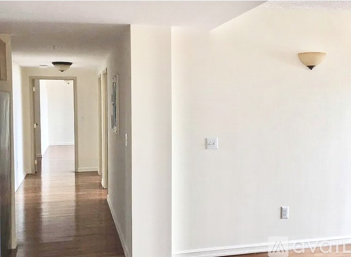 A long hallway with white walls and wood floors.