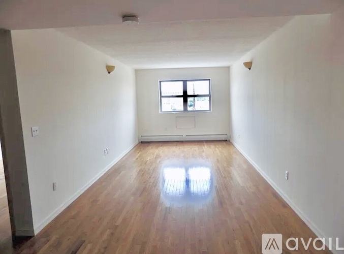 A spacious room with wooden floors and a window.