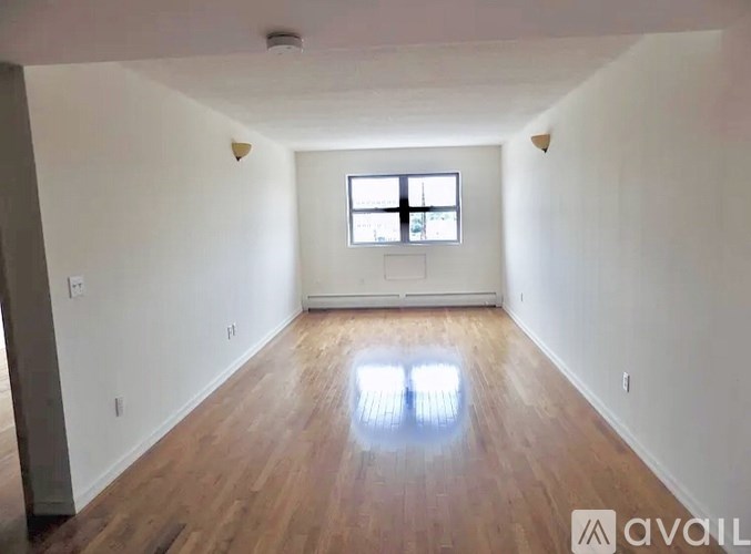 A spacious room with wooden floors and a window.