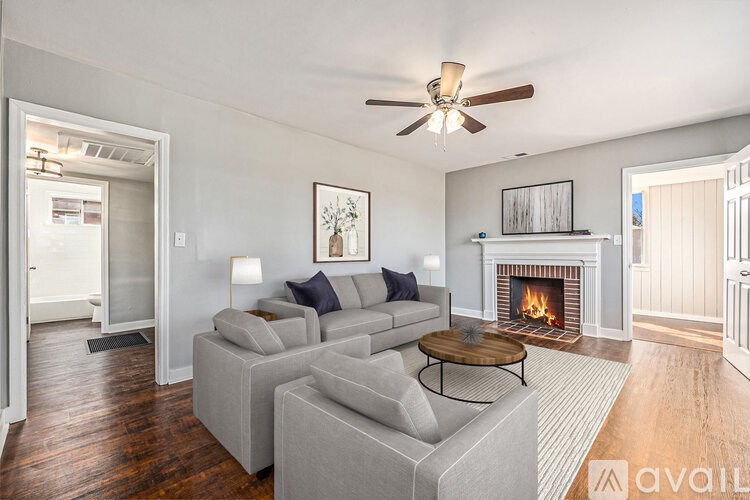 A living room with a grey couch, a fireplace, and a ceiling fan.