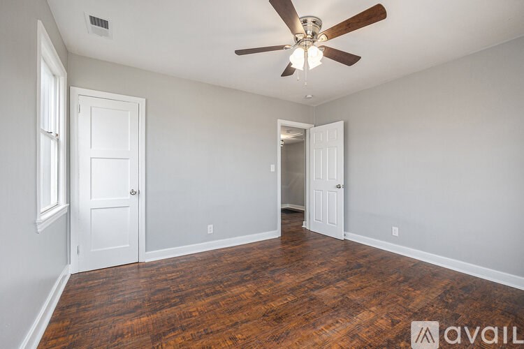 A room with a ceiling fan and wooden floors.
