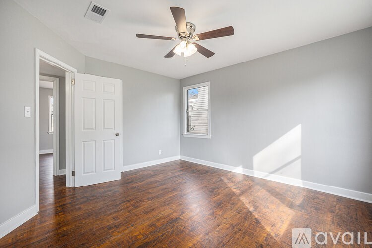 A room with a ceiling fan and wooden flooring.