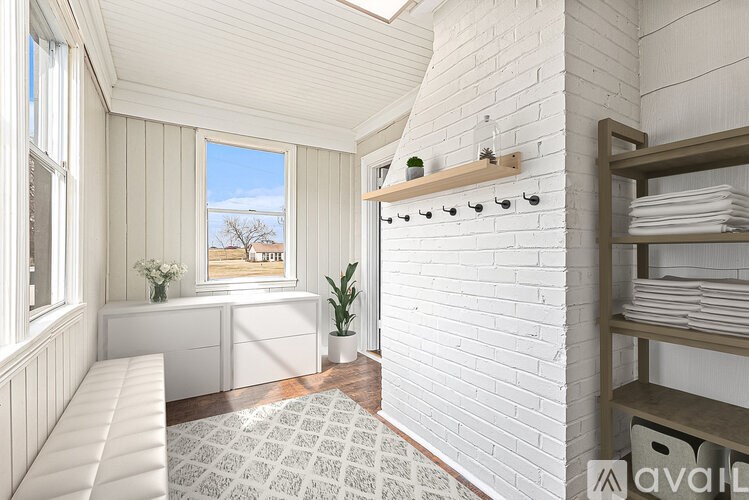 A white room with a window seat and a shelf with towels.