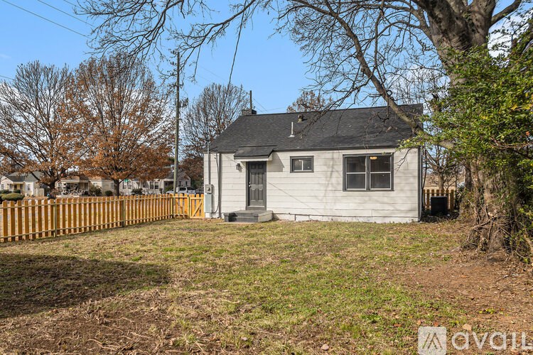 A small white house with a brown fence in front of it.