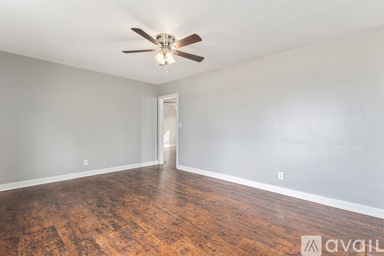 A room with a ceiling fan and wooden flooring.