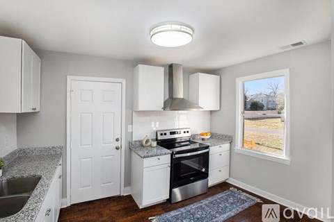 A kitchen with white cabinets and a window overlooking a yard.
