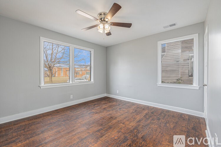 A room with a ceiling fan and a window with a view of a building.