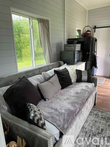 A grey couch with pillows sits in a room with a window.