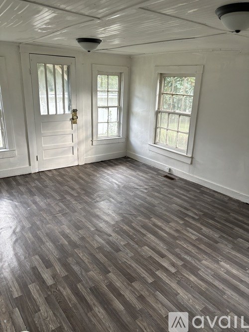 A room with wooden flooring and white walls.
