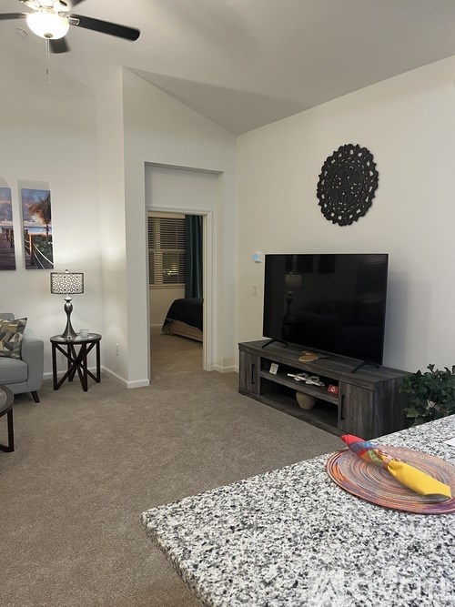 A living room with a grey couch, a black TV, and a white wall with a circular decoration.