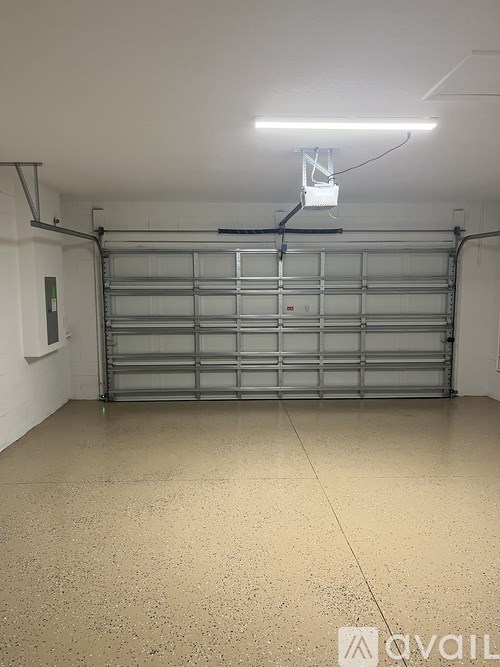 A garage with a closed shutter door and a light on.