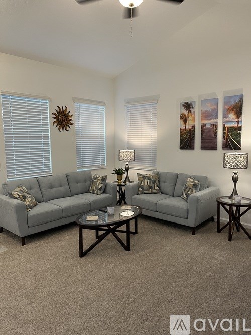 A living room with a grey sofa, a coffee table, and a ceiling fan.