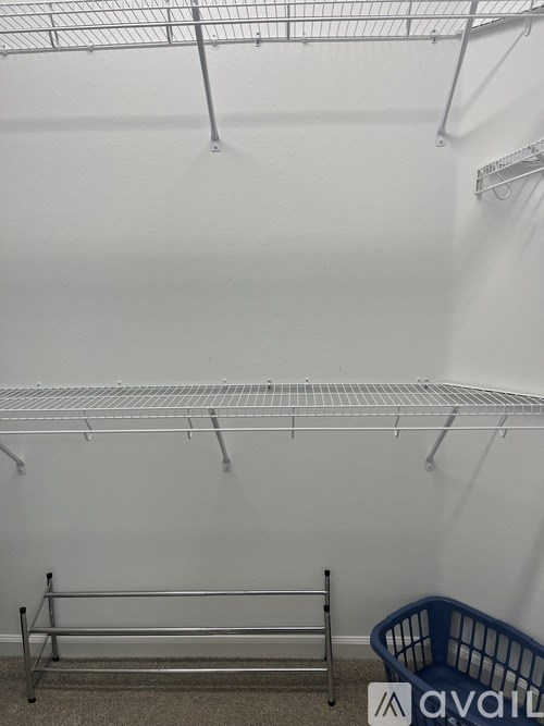 A room with a white wall and a metal shelf.