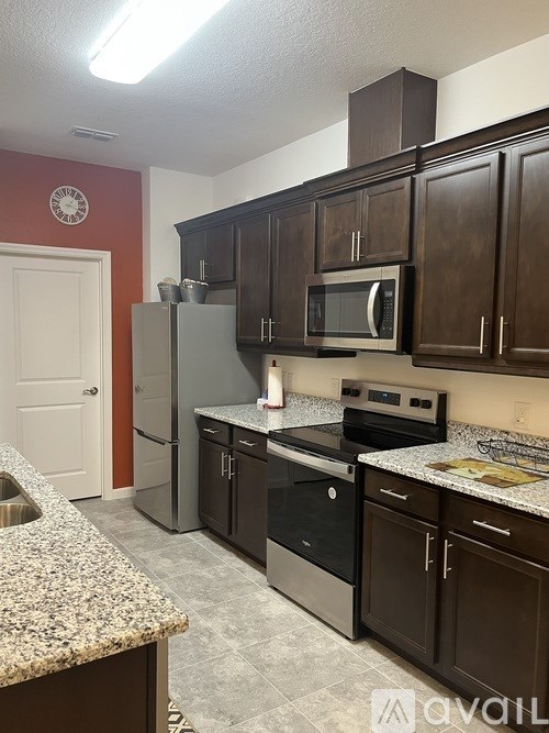 A kitchen with brown cabinets and a granite counter.
