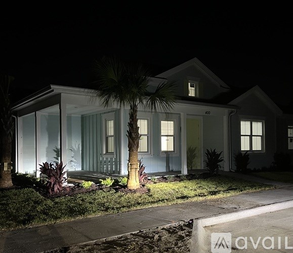 A house with a palm tree in front of it at night.