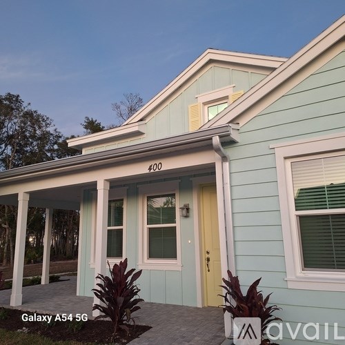 A blue house with a yellow door and a sign that says "Galaxy A54 5G" in front of it.