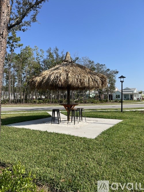 A thatched umbrella is in the middle of a grassy area.