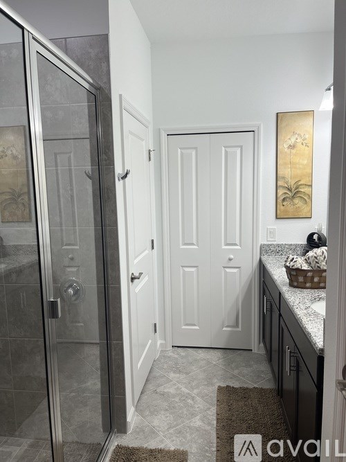 A bathroom with a glass shower door and a white door.