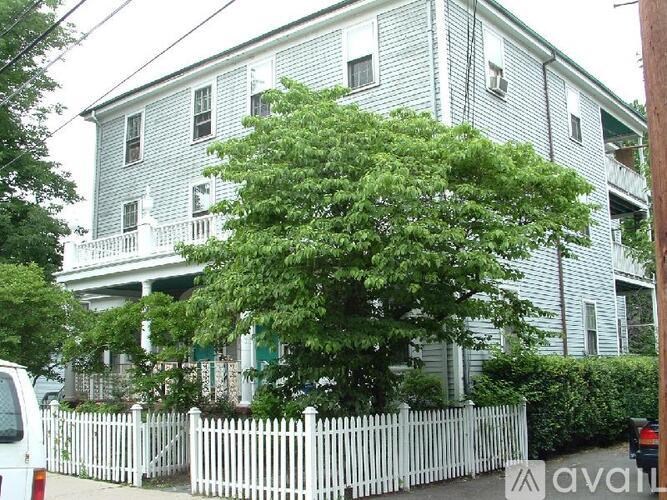 A white picket fence surrounds a two-story house.