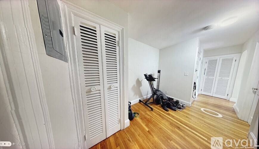 A room with a wooden floor, a pair of black shoes, and a black vacuum cleaner.