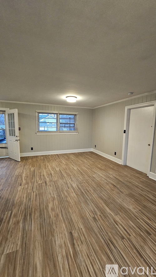 A room with wooden flooring and a window.