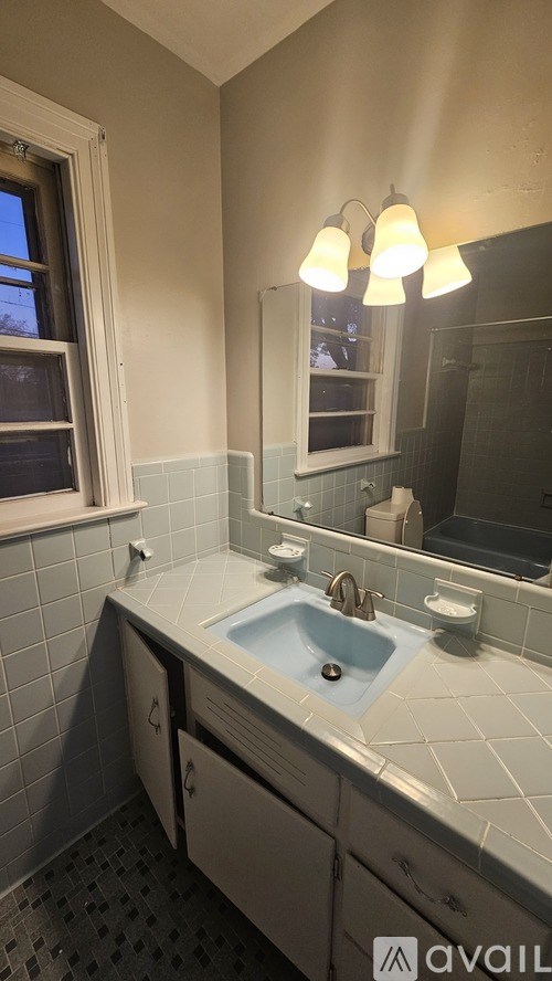 A bathroom with a sink, mirror, and a window.