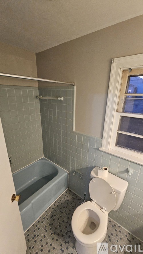 A bathroom with a toilet, tub, and tiled walls.