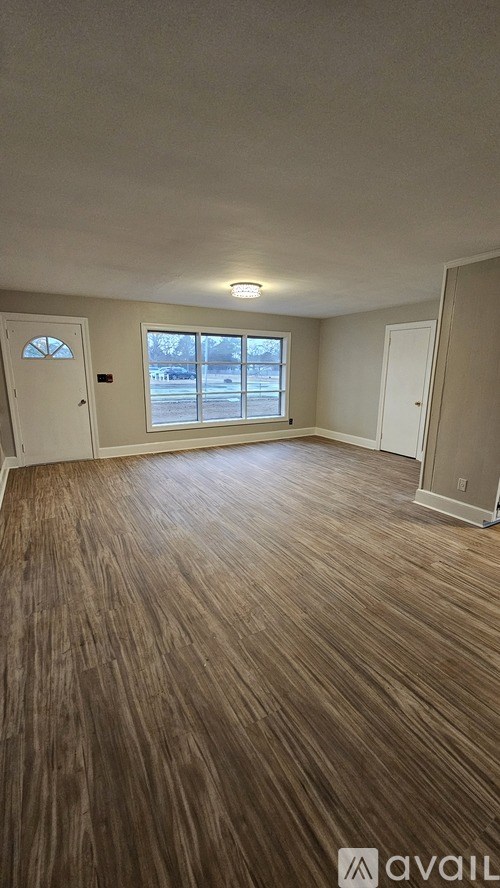 A room with wooden flooring and a window overlooking a snowy landscape.