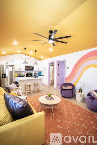 A living room with a yellow couch and a ceiling fan.
