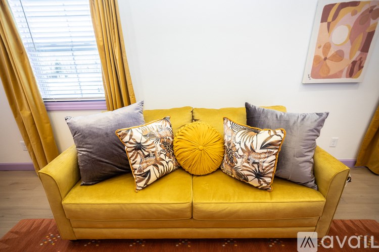 A yellow couch with four pillows on it.