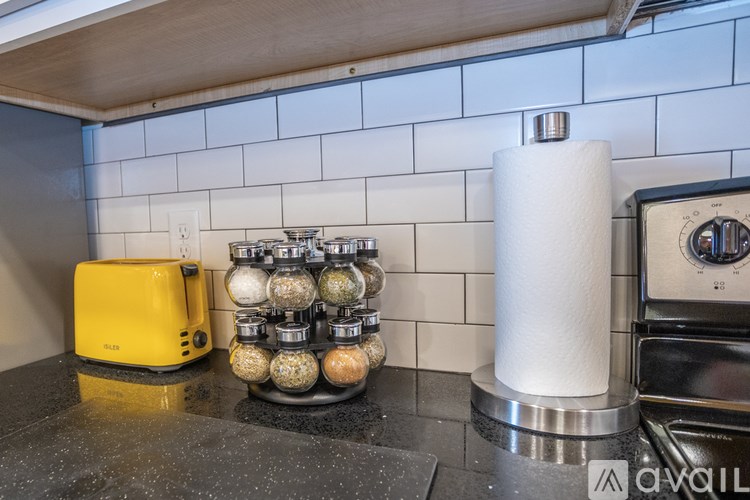 A yellow toaster is on a counter next to a stack of pepper shakers.