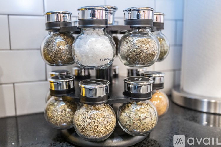 A set of glass jars with metal lids, each containing a different type of spice.