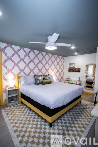 A bedroom with a bed, a fan, and a mirror.