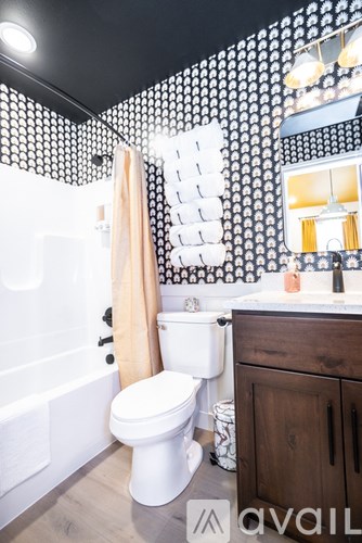 A bathroom with a toilet, a tub, and a mirror.