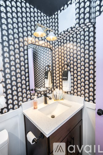A bathroom with a sink, toilet and a mirror with a black and white floral pattern.