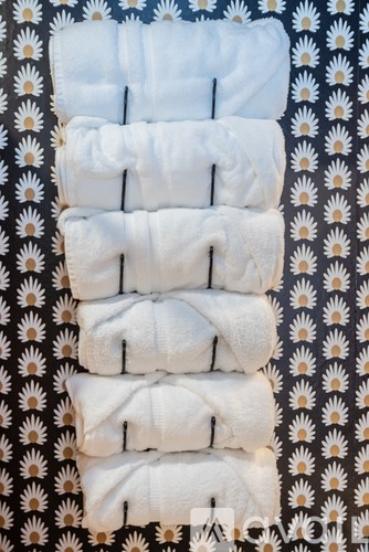 A stack of white towels on a black and white floral background.