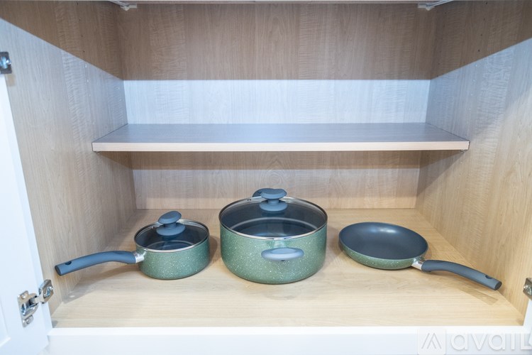A set of cookware is placed on a shelf in a kitchen cabinet.