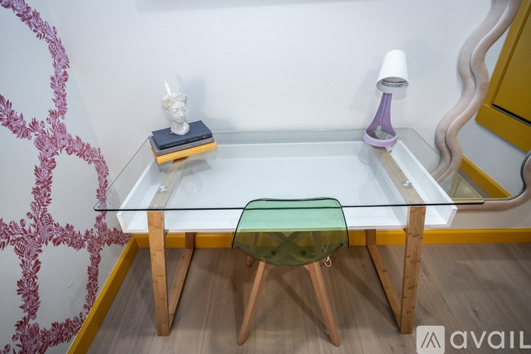 A glass table with a green cushion and wooden legs.