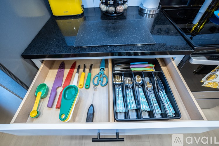 A drawer full of colorful knives and utensils.