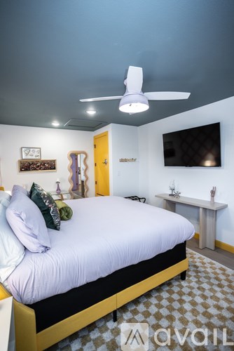 A bedroom with a bed, a fan, and a television.