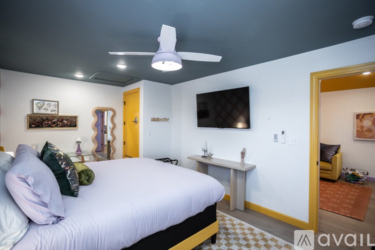 A bedroom with a bed, a TV, and a yellow door.