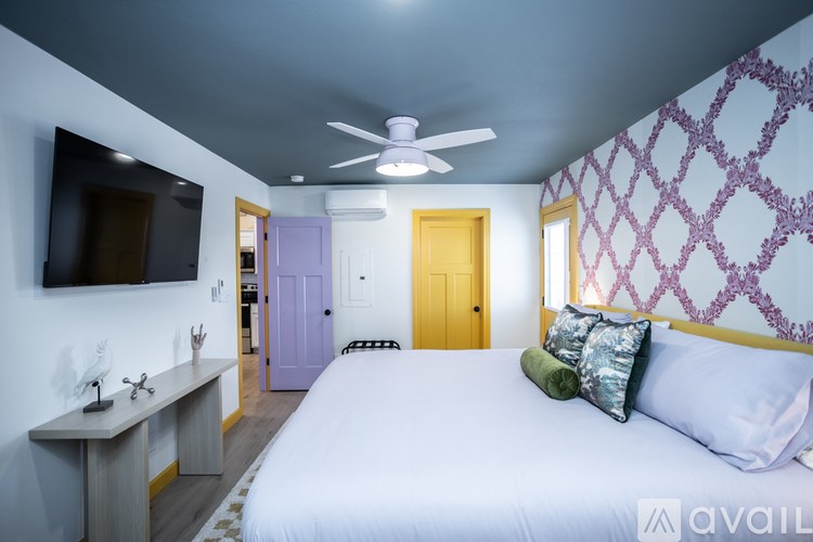 A bedroom with a bed, a desk, and a ceiling fan.