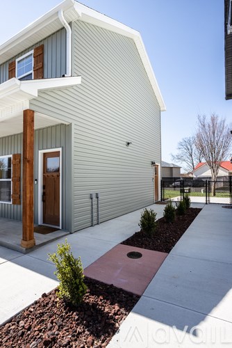 A modern house with a grey exterior and a red brick walkway in front.